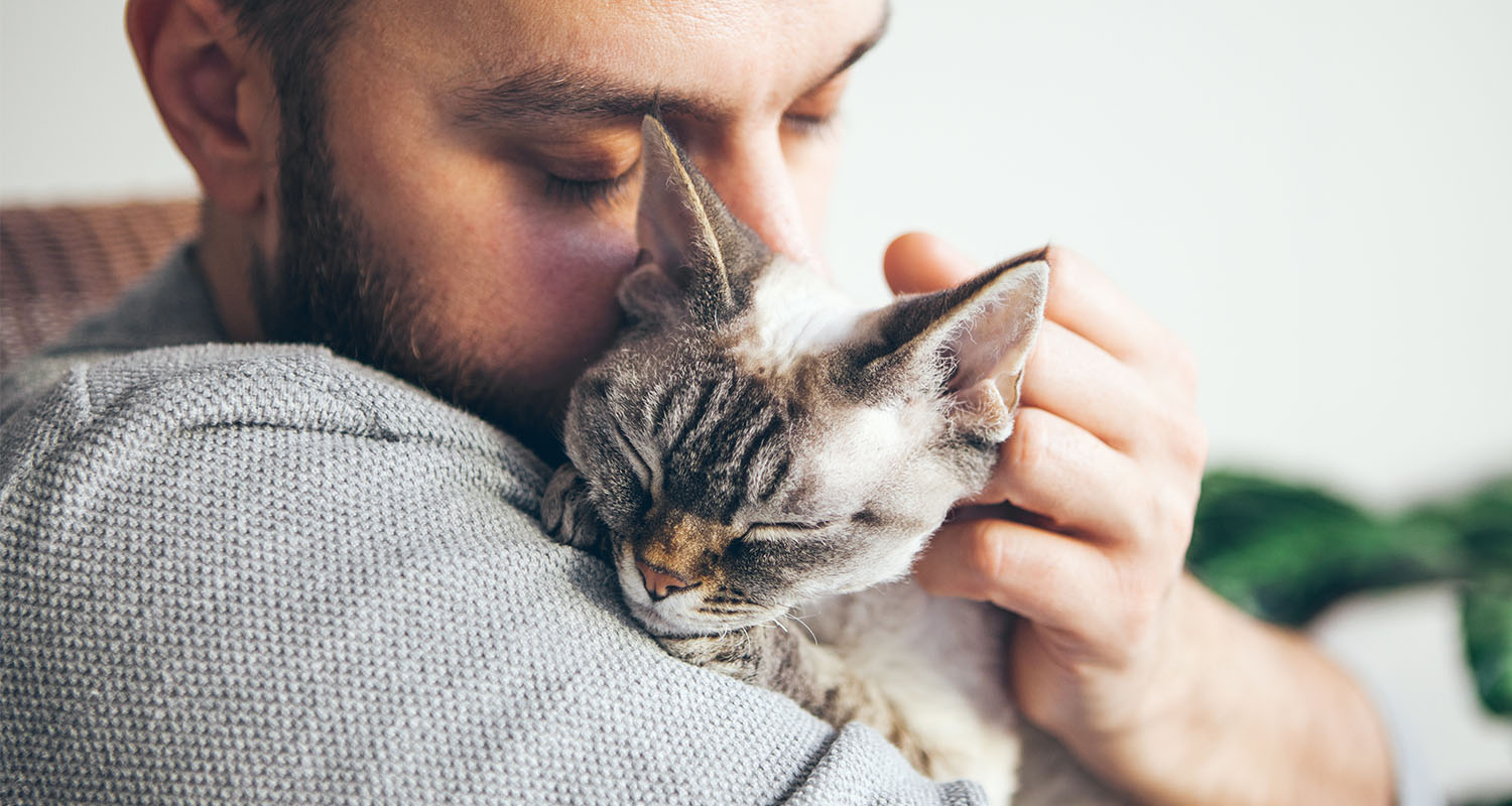 A man cuddling his cat after administering an inhaled bronchodilator.